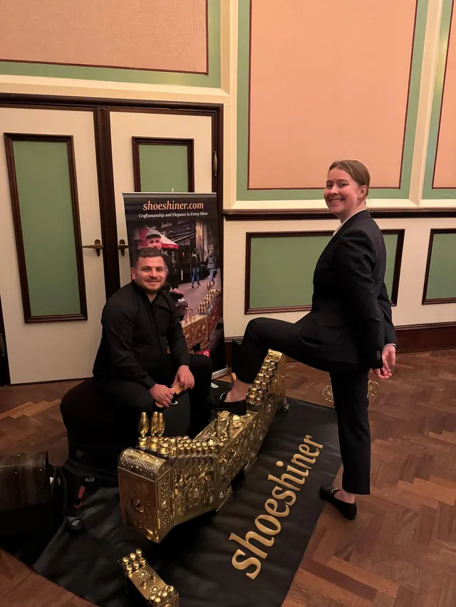 A guest seated with Shoeshiner during an indoor shoeshine.