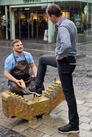 A conversation with a guest beside the shoeshine box in the city.