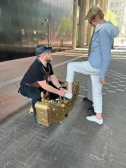 A guest in white trousers having their shoes cared for outdoors.