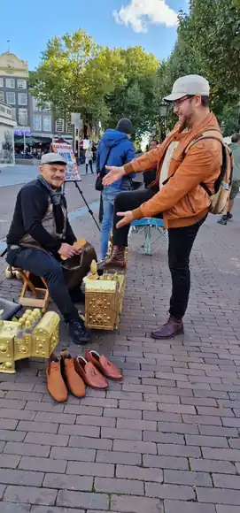 A guest in an orange jacket during an outdoor shoeshine.