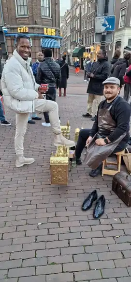 A guest beside the shoeshine box in a public square.