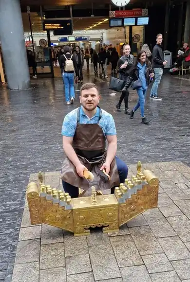 Shoeshiner seated behind the brass shoeshine box.