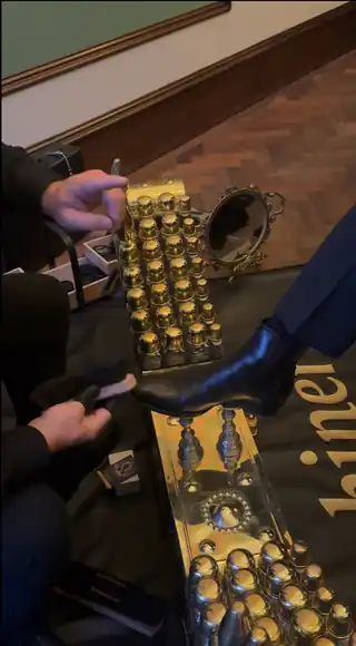 A close view of a shoe on the brass shoeshine box.