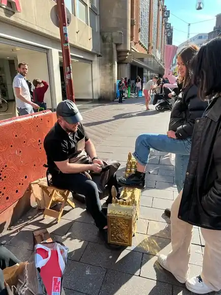 A guest seated on a bench during a shoeshine.