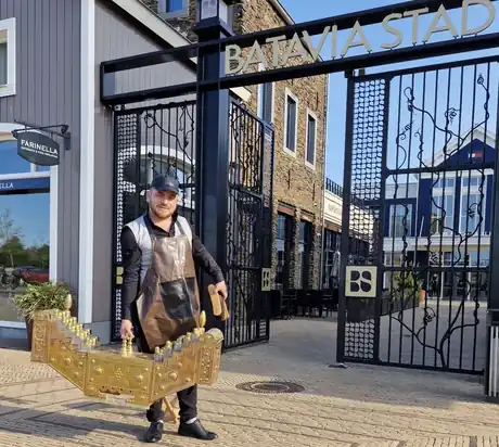 Shoeshiner carrying the brass shoeshine box outside Batavia Stad.